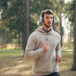 지루함을 이기는 귀의 마법: 플레이리스트와 팟캐스트 활용법 Man with headphones running in a forest