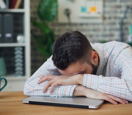 “늘 피곤한 당신, 만성피로 극복하는 ‘슬로우 라이프’ 바람” a man sitting at a desk with his head in his hands