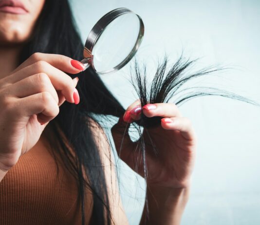 건강한 머릿결, 생활 습관이 먼저다… 실천 가능한 헤어 케어 트렌드 Woman examining split ends of hair with magnifying glass