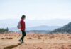 “저녁 산책, 달라지는 일상: 작은 움직임이 주는 큰 변화” a man with a backpack walking across a dry grass covered field