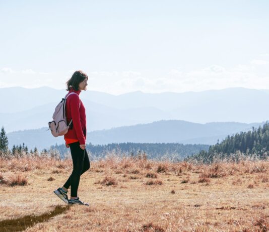 “저녁 산책, 달라지는 일상: 작은 움직임이 주는 큰 변화” a man with a backpack walking across a dry grass covered field